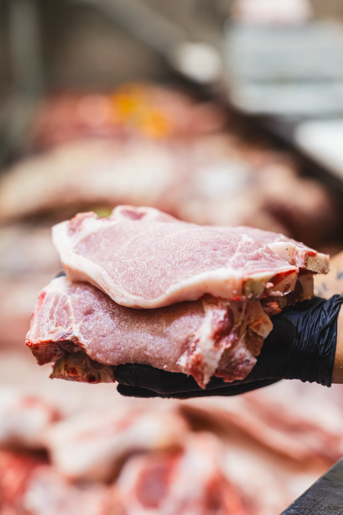 Chuletas de cerdo recién preparadas sostenidas por un operador.