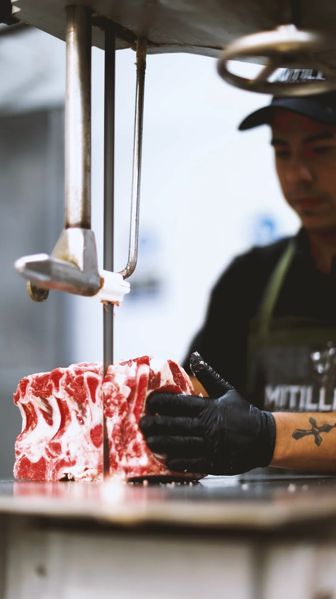 Integrante del equipo cortando carne con la sierra del local.